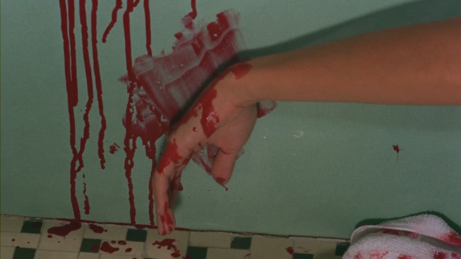 a hand smears fake blood on the wall