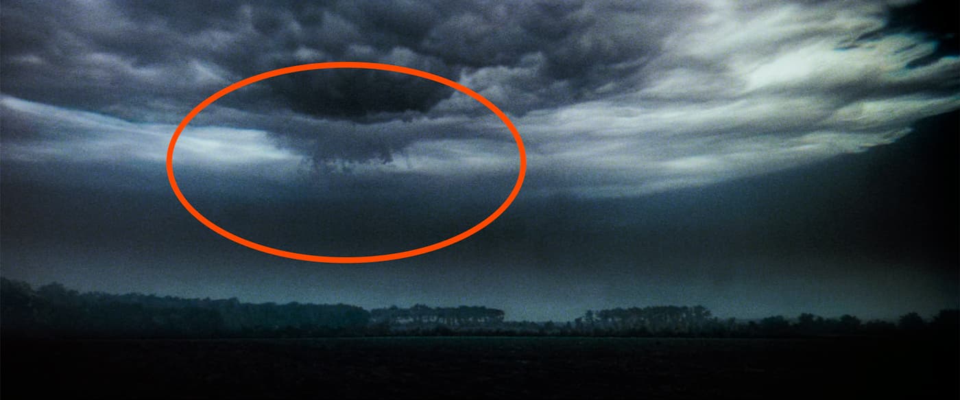 A wide angle view of a field with ominous clouds overhead