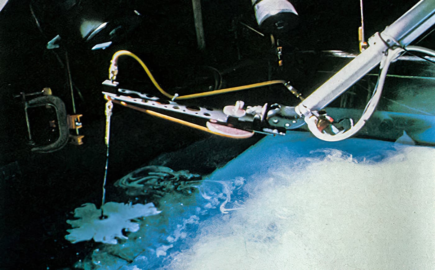 Robotic arm injects white ink into a large tank of water